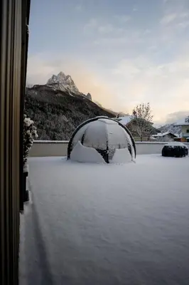 a snow covered yard with a view of a mountain at DOLOMITI EXCLUSIVE YOUR MOUNTAIN SUITE in Pozza di Fassa