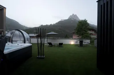 a yard with a tub and a table and chairs at DOLOMITI EXCLUSIVE YOUR MOUNTAIN SUITE in Pozza di Fassa