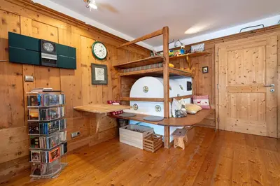 a room with wooden walls and a desk and a clock at Apartments Frea - Vedl Luech da Plajes in Ortisei
