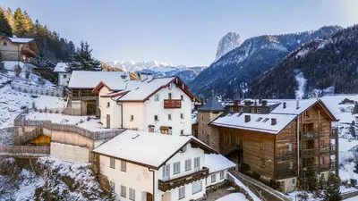 a village covered in snow with mountains in the background at Apartments Frea - Vedl Luech da Plajes in Ortisei