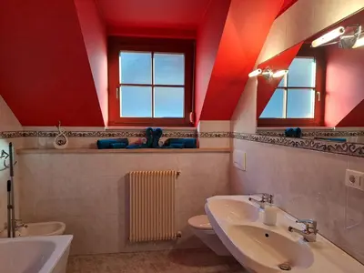 a bathroom with red walls and a sink and a toilet at Penthouse&Wellness L'Abete in Gargazzone