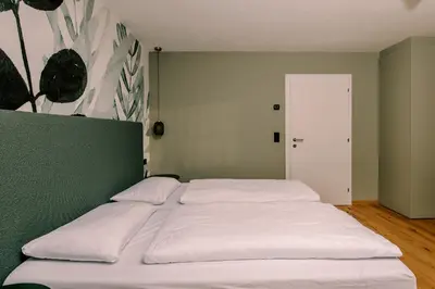 a white bed in a room with a green wall at The Nest – 85 qm apartment - Mountain, Ski, Relax in Vila di Sopra