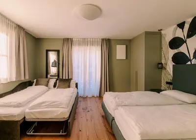 a hotel room with three beds and a window at The Nest – 85 qm apartment - Mountain, Ski, Relax in Vila di Sopra