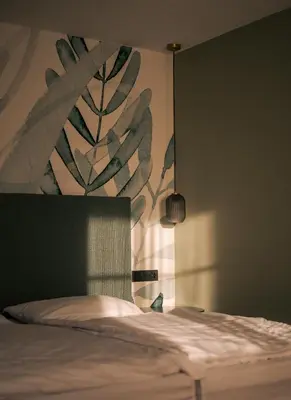 a bedroom with a bed with a plant mural on the wall at The Nest – 85 qm apartment - Mountain, Ski, Relax in Vila di Sopra