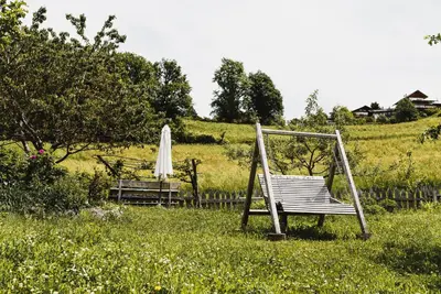 a swinging chair and an umbrella in a field at Unterplattnerhof in Chiusa