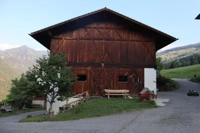 a large wooden barn with a bench in front of it at Unterplattnerhof in Chiusa