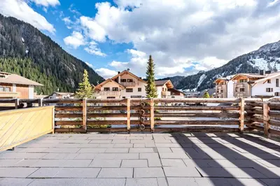 a wooden fence with houses and mountains in the background at ciasa monaco in Corvara in Badia