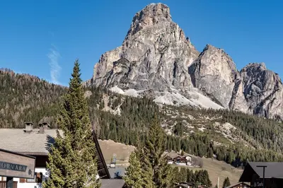 a mountain towering over a town in front of a building at ciasa monaco in Corvara in Badia