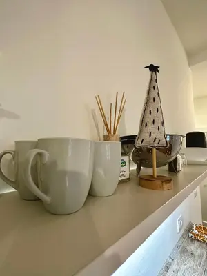 two white cups sitting on a counter with a small sailboat at Baker House in Bolzano