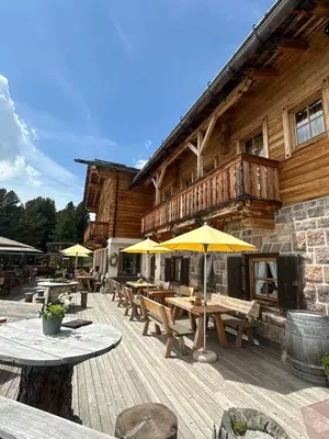 a wooden deck with tables and umbrellas in front of a building at Chalet Resciesa Ortisei in Ortisei