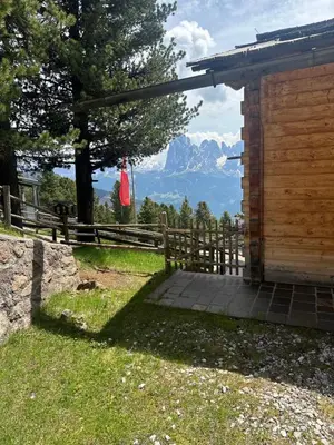 a wooden cabin with a fence and mountains in the background at Chalet Resciesa Ortisei in Ortisei