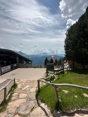 a bench in the grass near a building with mountains at Chalet Resciesa Ortisei in Ortisei