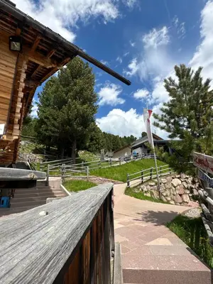 a wooden walkway leading to a building with a flag at Chalet Resciesa Ortisei in Ortisei