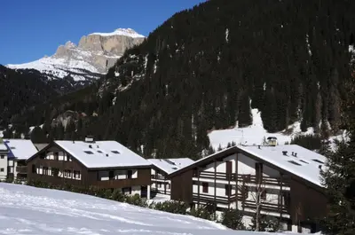 a lodge in the snow with a mountain in the background at Casa Canazei in Canazei
