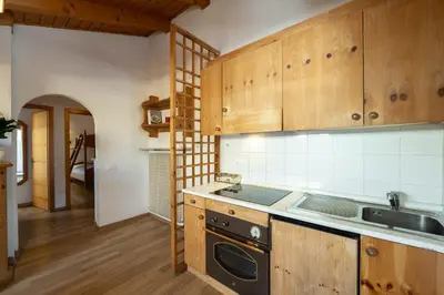 a kitchen with wooden cabinets and a sink and a stove at Casa Canazei in Canazei