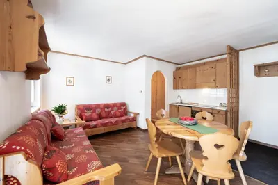a living room with a table and a red couch at Casa Canazei in Canazei
