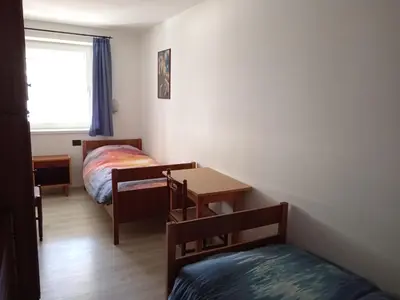 a bedroom with two beds and a table and a desk at Ciasa del Faure in Pozza di Fassa