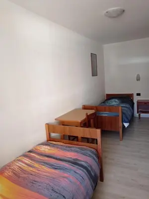 a bedroom with a bed and a desk and a bed and a table at Ciasa del Faure in Pozza di Fassa