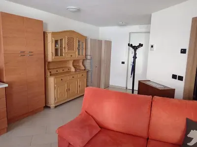a living room with a red couch and a wooden cabinet at Ciasa del Faure in Pozza di Fassa