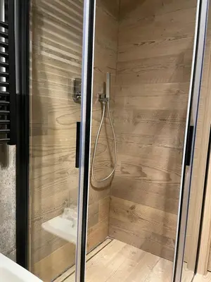 a shower with a glass door in a bathroom at Nuovo e comodo in Val di Fassa in Campitello