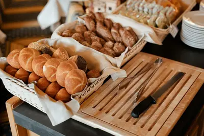 a table topped with baskets of bread and pastries at Hotel Cristallo in Santa Cristina in Val Gardena