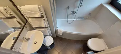 a bathroom with a tub and a toilet and a sink at Hotel Cristallo in Santa Cristina in Val Gardena
