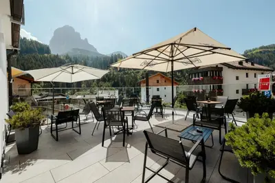 a patio with tables and chairs and umbrellas at Hotel Cristallo in Santa Cristina in Val Gardena