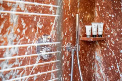 a bathroom with a shower with three candles on a wall at CORTINA Lodge in Cortina dʼAmpezzo