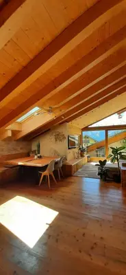 a large room with a wooden ceiling with a table and chairs at Berg Apartments - Appartamento famigliare moderno in Stava