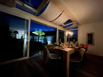 a dining room table with chairs and a large window at Guesthouse Le Palme in Postal