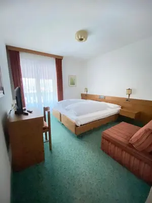 a bedroom with a bed and a television in it at Affittacamere Garden Cavalese in Cavalese