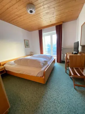 a bedroom with a large bed and a window at Affittacamere Garden Cavalese in Cavalese