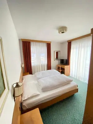 a bedroom with a large bed in a room with windows at Affittacamere Garden Cavalese in Cavalese