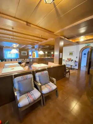 a living room with two chairs and a kitchen at Affittacamere Garden Cavalese in Cavalese