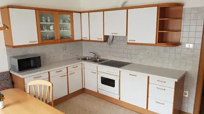 a kitchen with white cabinets and a sink and a table at Feldlechn in Lappago