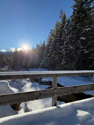 a fence covered in snow with the sun in the background at Felda Appartements in Lappago