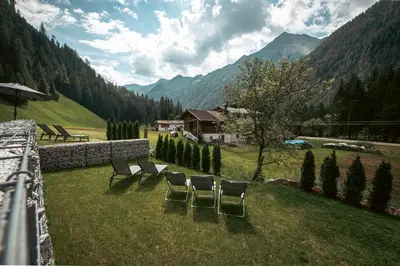 a group of chairs sitting on a field with mountains at Felda Appartements in Lappago