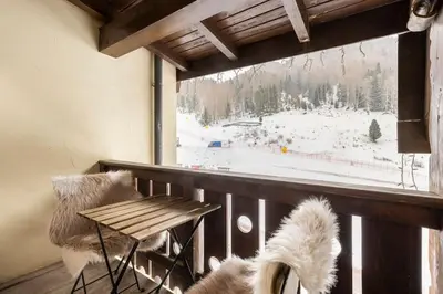 a balcony with a table and a view of a snow covered mountain at Dolomiti Haus - Immerso nelle Dolomiti in Tesero