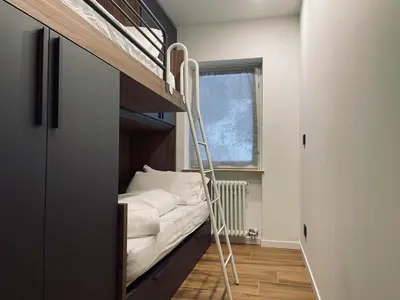a bunk bed with a ladder in a room at Dolomiti Haus - Immerso nelle Dolomiti in Tesero