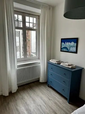 a bedroom with a blue dresser and a window at Townhouse Bozen in Bolzano