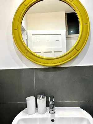 a bathroom with a yellow mirror above a sink at Townhouse Bozen in Bolzano