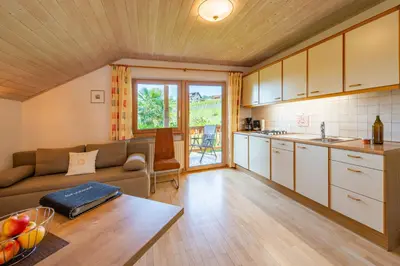 a living room with a couch and a kitchen at Gfillhof Ferienwohnung 2 in Appiano sulla Strada del Vino
