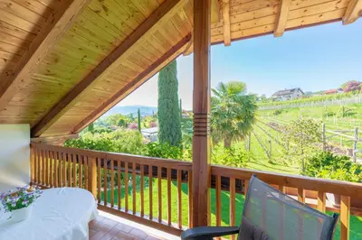 a wooden porch with a table and chairs on a balcony at Gfillhof Ferienwohnung 2 in Appiano sulla Strada del Vino
