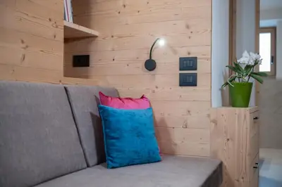 a gray couch with a blue and pink pillow at Apartments Corcela in San Vigilio Di Marebbe