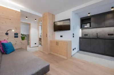 a living room with a couch and a kitchen at Apartments Corcela in San Vigilio Di Marebbe