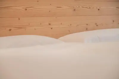 a bed with white sheets and a wooden headboard at Apartments Corcela in San Vigilio Di Marebbe
