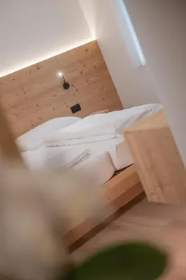 a bed in a room with a wooden floor at Apartments Corcela in San Vigilio Di Marebbe