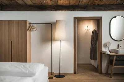 a bedroom with a bed and a lamp and a mirror at Ansitz Heufler by Norbert Niederkofler in Rasun di Sopra