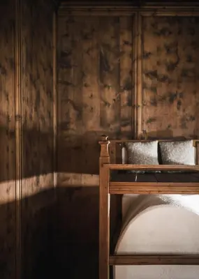 a bed in a room with a wooden wall at Ansitz Heufler by Norbert Niederkofler in Rasun di Sopra