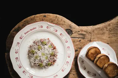 a plate of rice and bread on a wooden table at Ansitz Heufler by Norbert Niederkofler in Rasun di Sopra